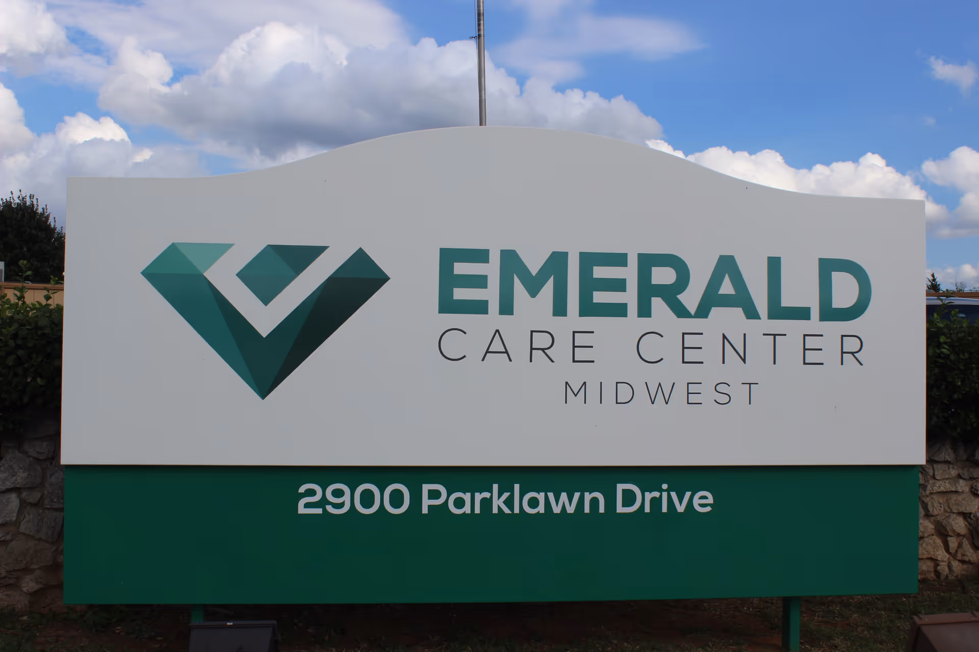 Outdoor sign for Emerald Care Center Midwest displaying the logo and the address "2900 Parklawn Drive".