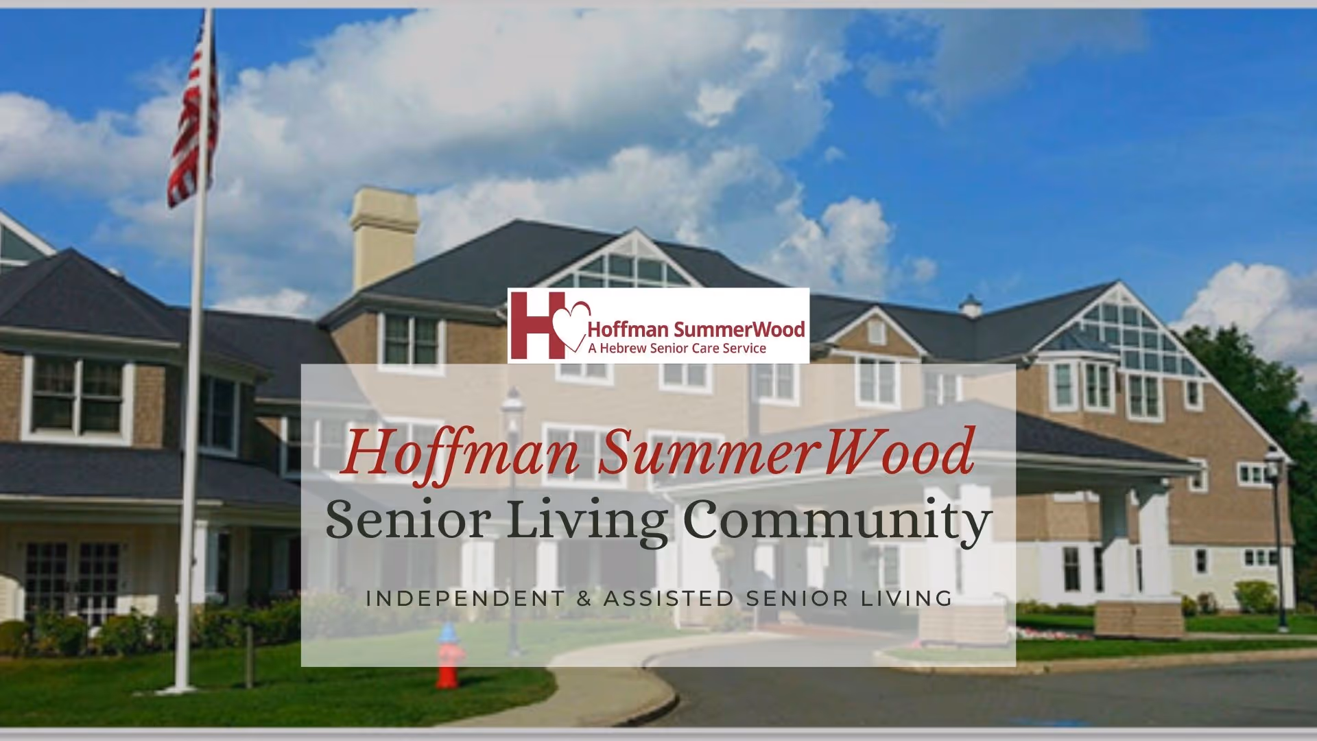 Front exterior of the Hoffman SummerWood senior living community building with an American flag and a large overlaid facility name sign.