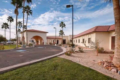 Exterior view of Life Care Center of Yuma with arches, palm trees, and parking.