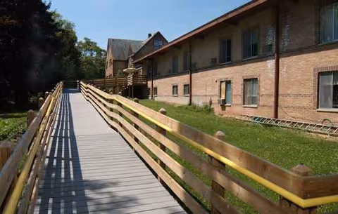 Brick retirement home building with a wooden ramp along an exterior walkway.