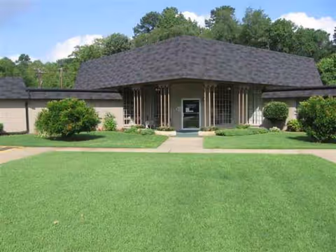 Front view of Pine Tree Lodge Nursing Center with a lawn and entrance.