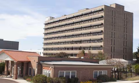 Exterior view of Parkhouse Nursing & Rehabilitation Center showing a tall building beside a brick entrance.