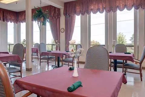 Crestwood Health and Rehab dining room with pink tablecloths and large windows.