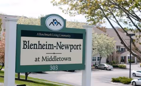 A green-and-white Blenheim-Newport sign at Middletown in front of a building