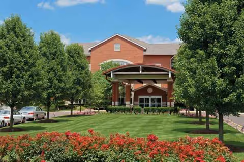 Front view of Ann's Choice retirement community entrance with brick façade and landscaped grounds.