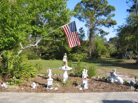 Outdoor garden scene with small statues and a waving American flag.