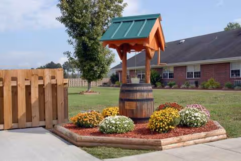 Front exterior of a brick senior living facility with a decorative well and flowers.