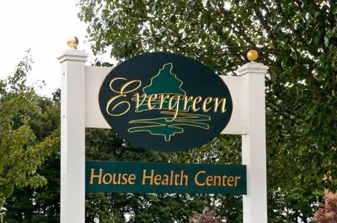 Exterior sign for Evergreen House Health Center with green logo.