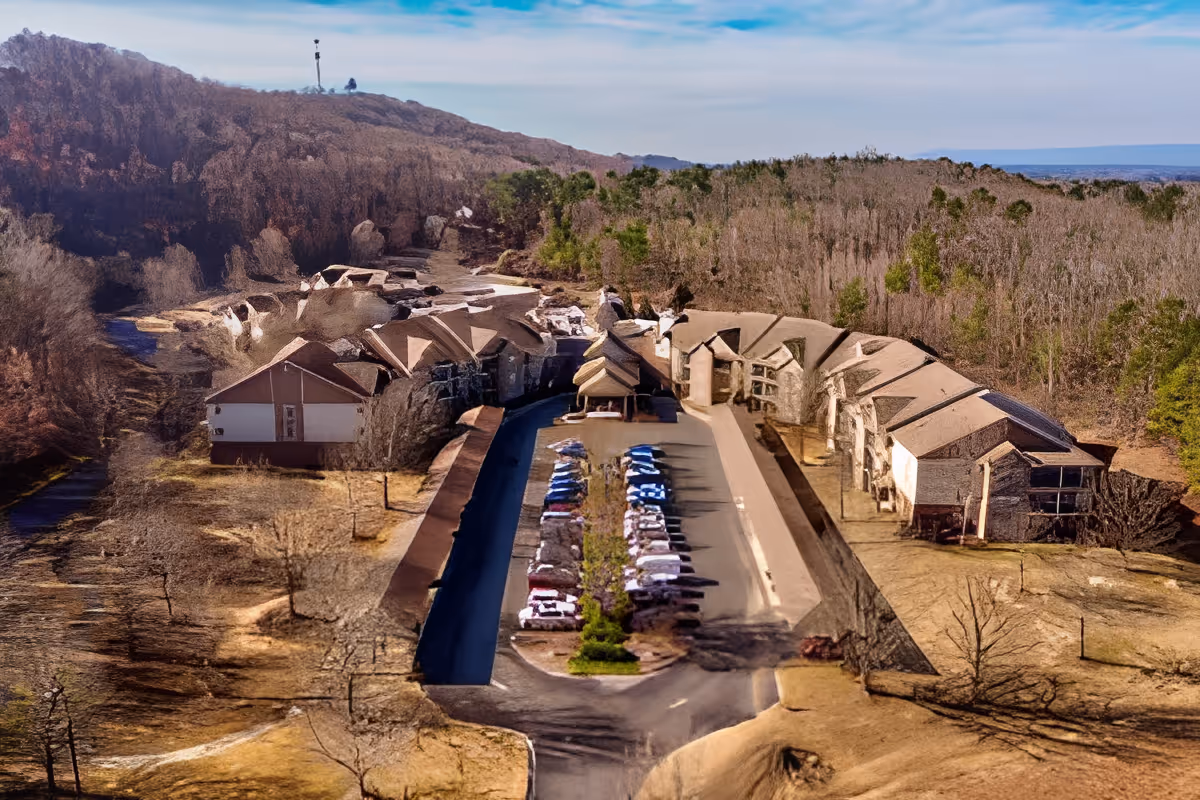 Aerial view of The Haven at Regency Pointe facility showing a U-shaped building surrounded by trees and hills, with a parking lot filled with cars in the center.