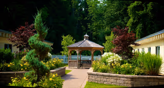 Outdoor courtyard with a wooden gazebo, planters, and lush garden landscaping.