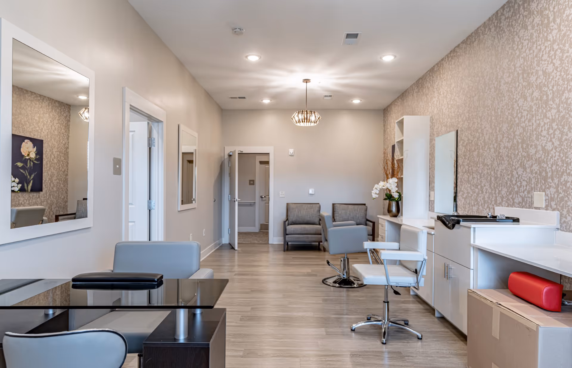 Well-lit salon area with styling chairs, mirrors, workstations and seating in a modern interior.