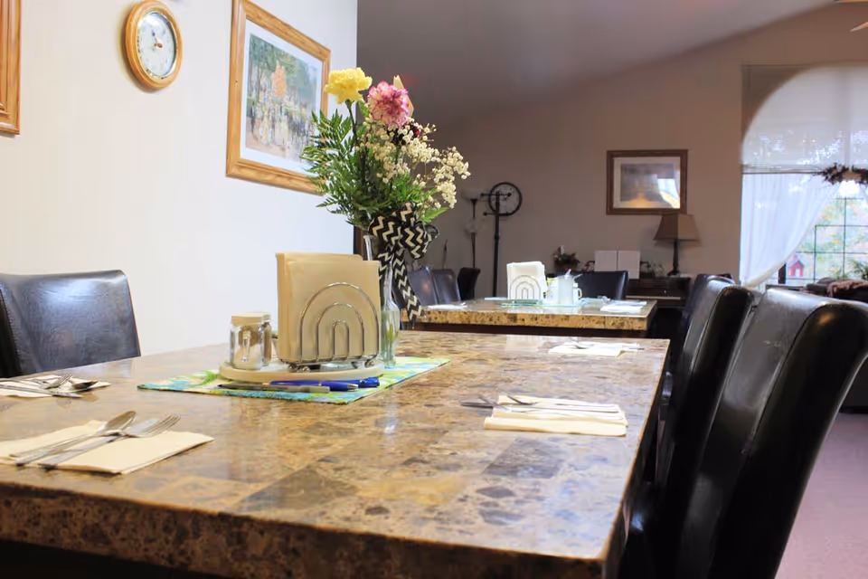 Granite dining table with utensils and a flower centerpiece in a senior living dining room.