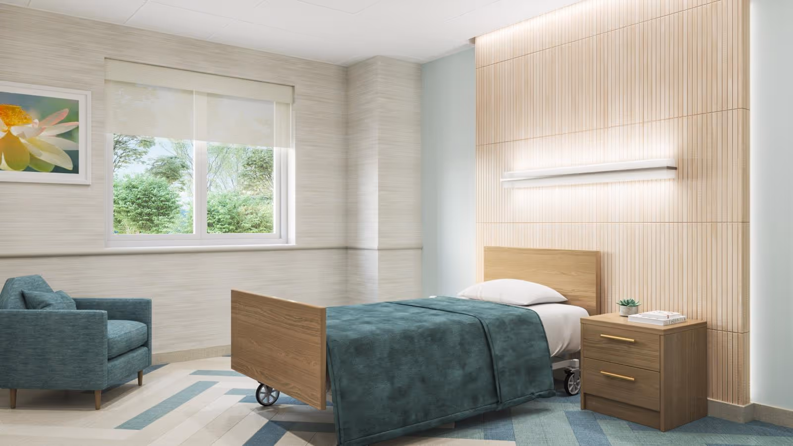 A bright and clean nursing facility bedroom with a single hospital bed covered in a teal blanket, a wooden nightstand with a small plant and books, a teal armchair, a window showing greenery outside, and a framed flower picture on the wall.