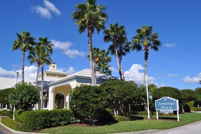 Entrance of Somerset House at Oak Harbor with palm trees and a sign