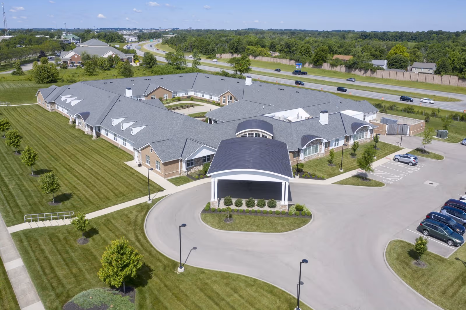 Aerial view of Kauhale Centerville senior living facility showing a single-story building with a covered entrance, surrounding lawns, parking lot and nearby road.