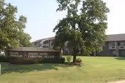 Front view of a brick senior living facility with a well-kept lawn and sign.