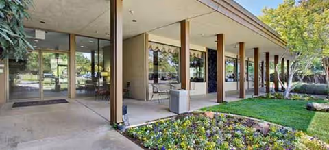 Exterior view of a senior living facility with glass doors, columns, and landscaped entry.