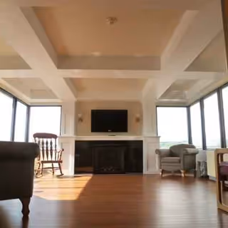 Bright living room with fireplace, large windows, wooden floor, and seating.