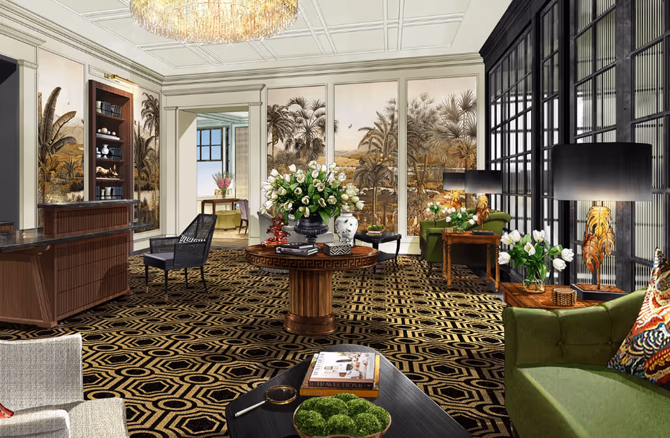 A luxurious living room with patterned carpet, green upholstered sofas, wooden tables with lamps and flower vases, and large wall panels featuring tropical-themed artwork. The room has a coffered ceiling with a chandelier and large windows with black frames letting in natural light.