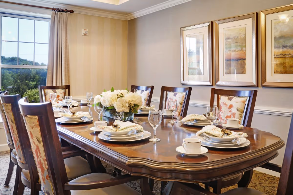 Elegant dining room with a wooden table set for a meal, a floral centerpiece, and upholstered chairs.