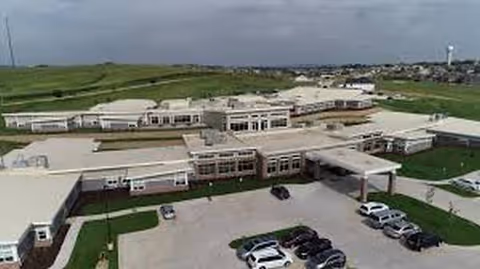 Aerial view of Heritage Manor campus with connected buildings, parking lot, and surrounding green fields.