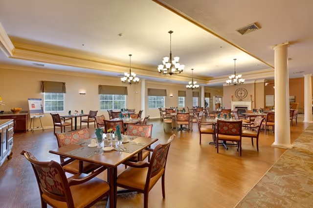 Spacious, well-lit dining room with multiple set tables, chandeliers, and a fireplace.