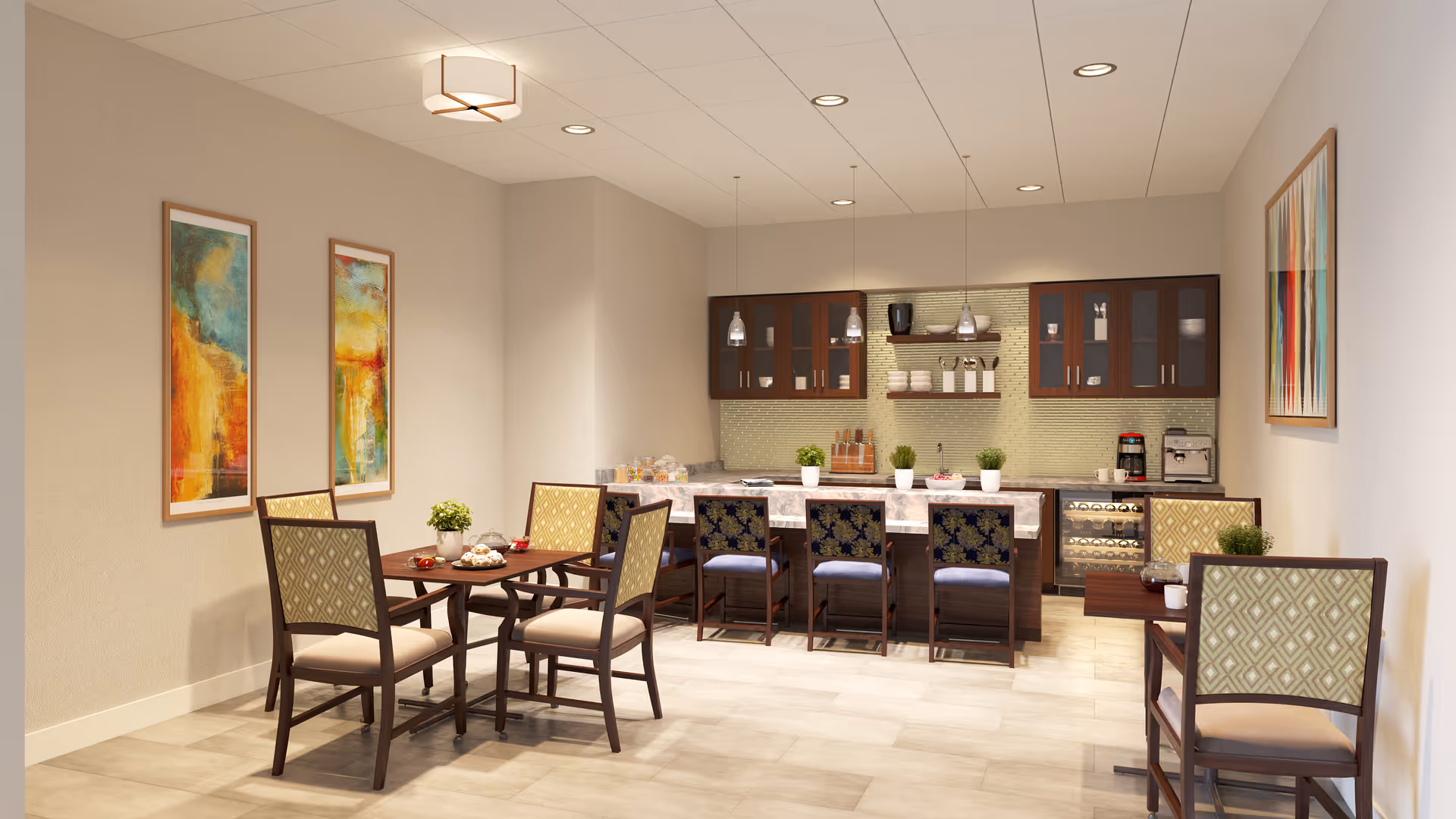 A modern dining area in a senior living facility featuring a kitchen with dark wood cabinets, a marble countertop island with four chairs, and two small dining tables each with two chairs. The walls are decorated with colorful abstract paintings, and the room is well-lit with ceiling lights and pendant lamps over the island.