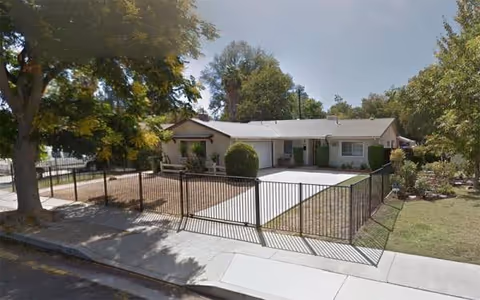 Single-story senior living home exterior with a metal gate and manicured front yard.
