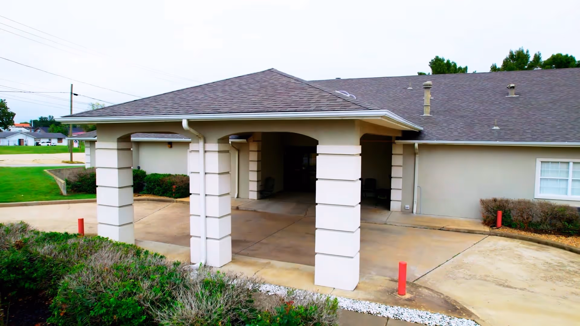 Covered front entrance with square columns and a drive-up canopy at a single-story senior living building.