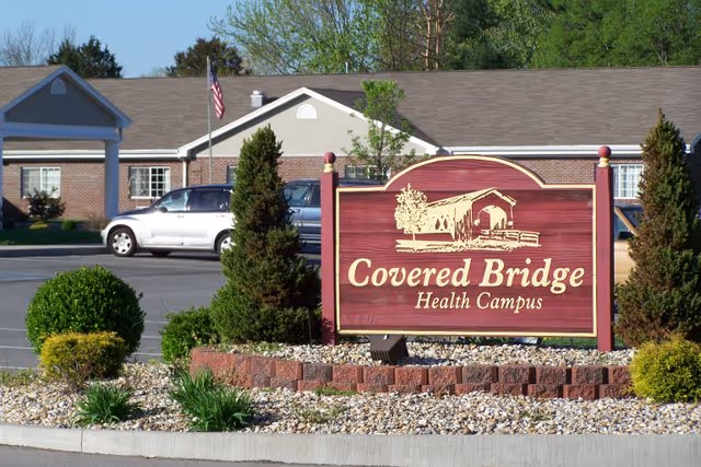 A landscaped entrance sign reading "Covered Bridge Health Campus" in front of a one-story brick building.
