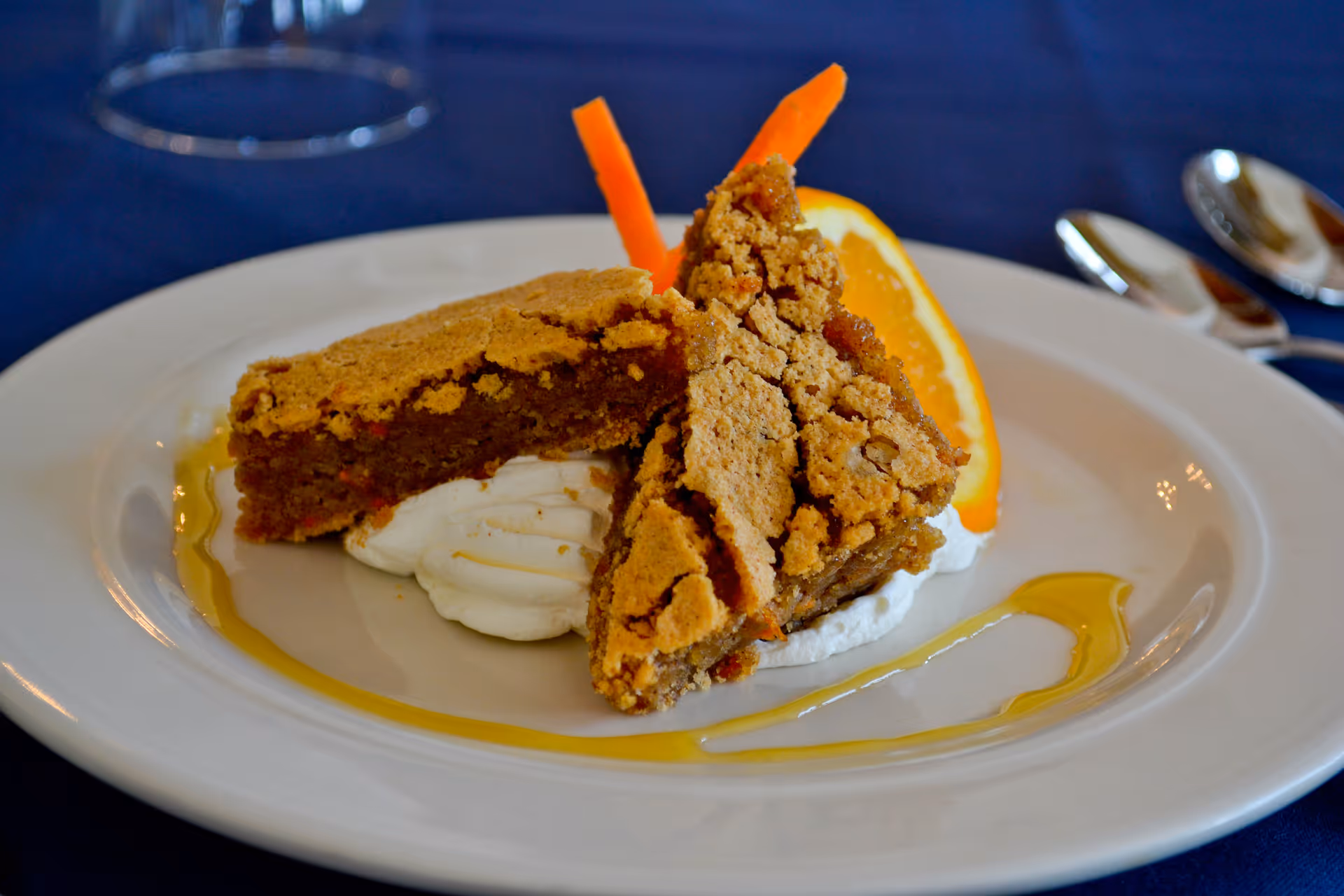 Two slices of pie served with whipped cream, an orange wedge, and a drizzle of sauce on a white plate.