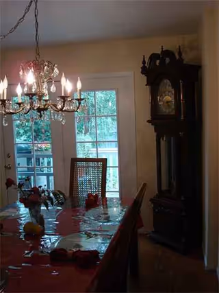 Dining room with chandelier, table set for a meal, and a tall grandfather clock.
