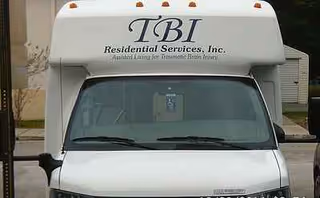 Front view of a white TBI Residential Services, Inc. bus with logo.