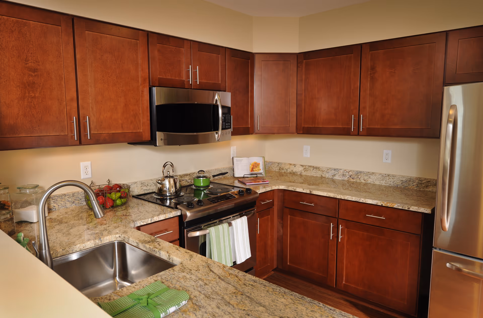 Modern kitchen with stainless steel appliances, wooden cabinets, granite countertops and a sink.