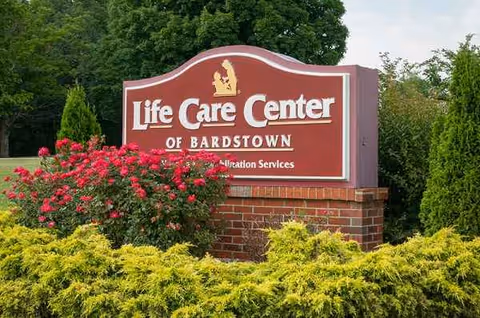Exterior Life Care Center of Bardstown sign framed by shrubs and greenery.