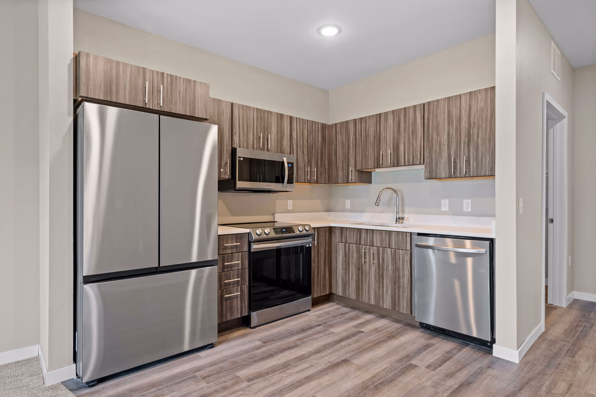 Modern kitchen with stainless steel appliances and wood grain cabinets.