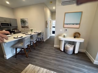 Open-plan kitchen and dining area with a breakfast bar and four stools, appliances, and a small console table against a wall.