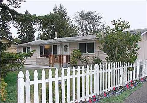 Front view of a single-story facility with white picket fence and landscaped yard.