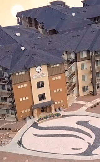Aerial view of the Bonaventure of Pueblo building entrance featuring a landscaped courtyard with a decorative stone design and the facility's signage.