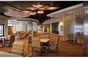 Communal dining/lounge area with tables and upholstered chairs, decorative ceiling lighting, and partition screens.