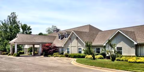 Front exterior view of Ambassadors Courtyards with landscaped grounds and a covered entrance.