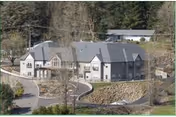 A large, two-story retirement village building named Rock of Ages Valley View Retirement Village, surrounded by trees and greenery with a curved driveway leading to the entrance.