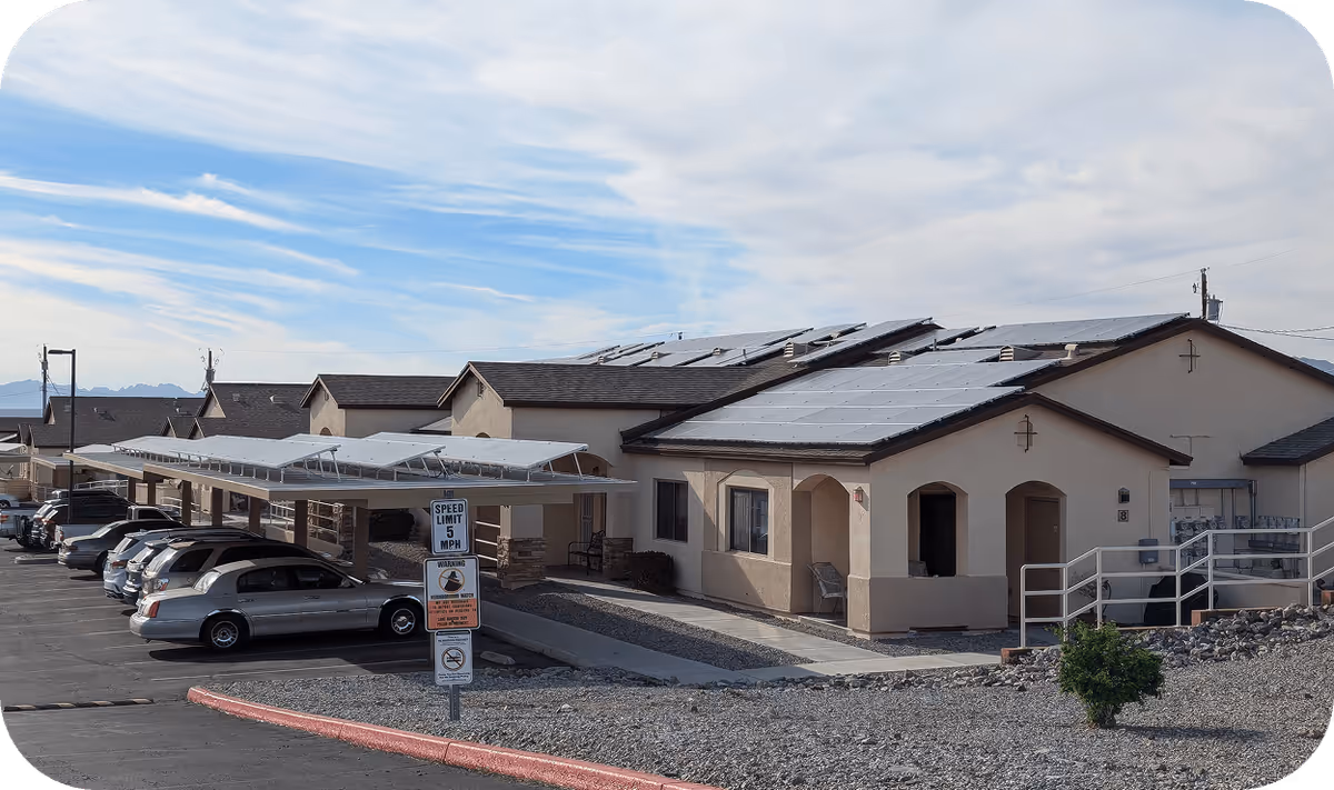 Exterior view of AllThrive 365 facility with parked cars and solar-paneled roofs.