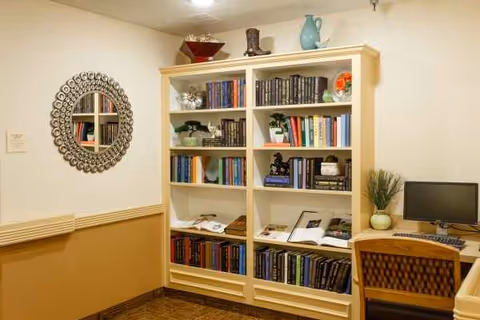 Cozy library area with a tall bookshelf, round decorative mirror, and computer desk.