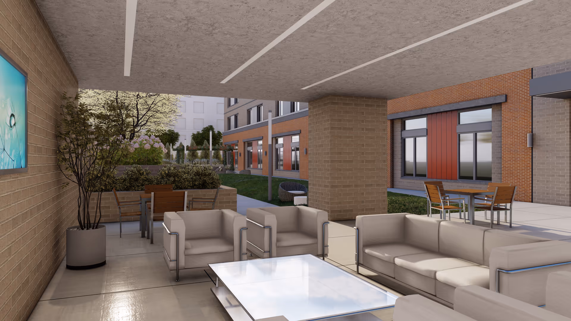 Covered outdoor seating area with modern beige sofas and armchairs around a glass coffee table. In the background, there are additional tables and chairs on a patio with greenery, trees, and a brick building with large windows.