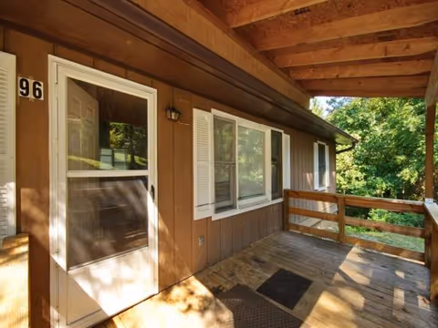 Brown wood exterior with a porch, door, windows, and railing along the building front.