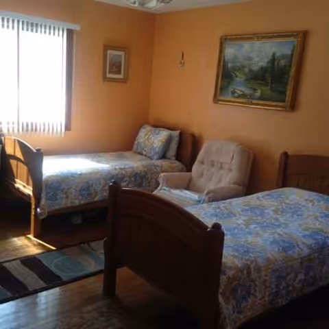 Two single beds with blue floral bedspreads in a peach-colored bedroom.
