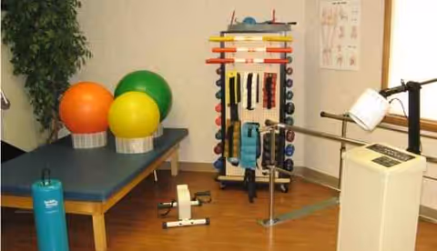 Rehabilitation exercise room with exercise balls, weights, and parallel bars.