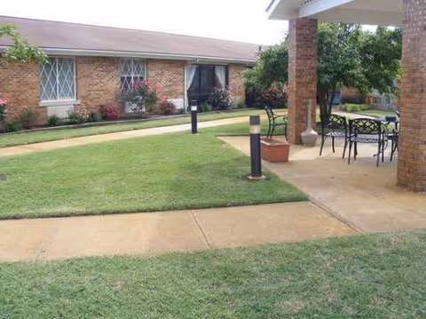 Outdoor courtyard of a brick senior living facility with patio seating.