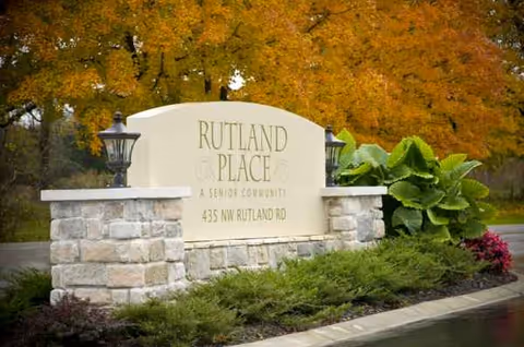 Stone Rutland Place sign with landscaping and autumn trees in front.